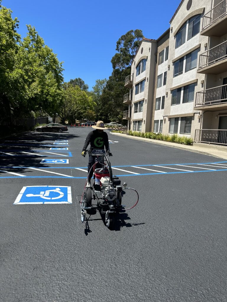 Workers applying fresh paint lines on a parking surface, How to paint parking Lot Lines for your business - Parking Lot Maintenance