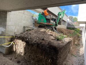 Preparing the ground for the retaining wall construction project under HT Paving and Sealcoating's expertise.