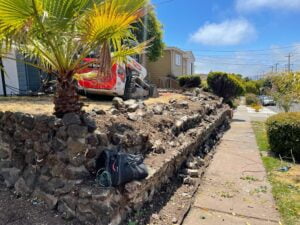 Terrain analysis and leveling before retaining wall construction by HT Paving and Sealcoating.